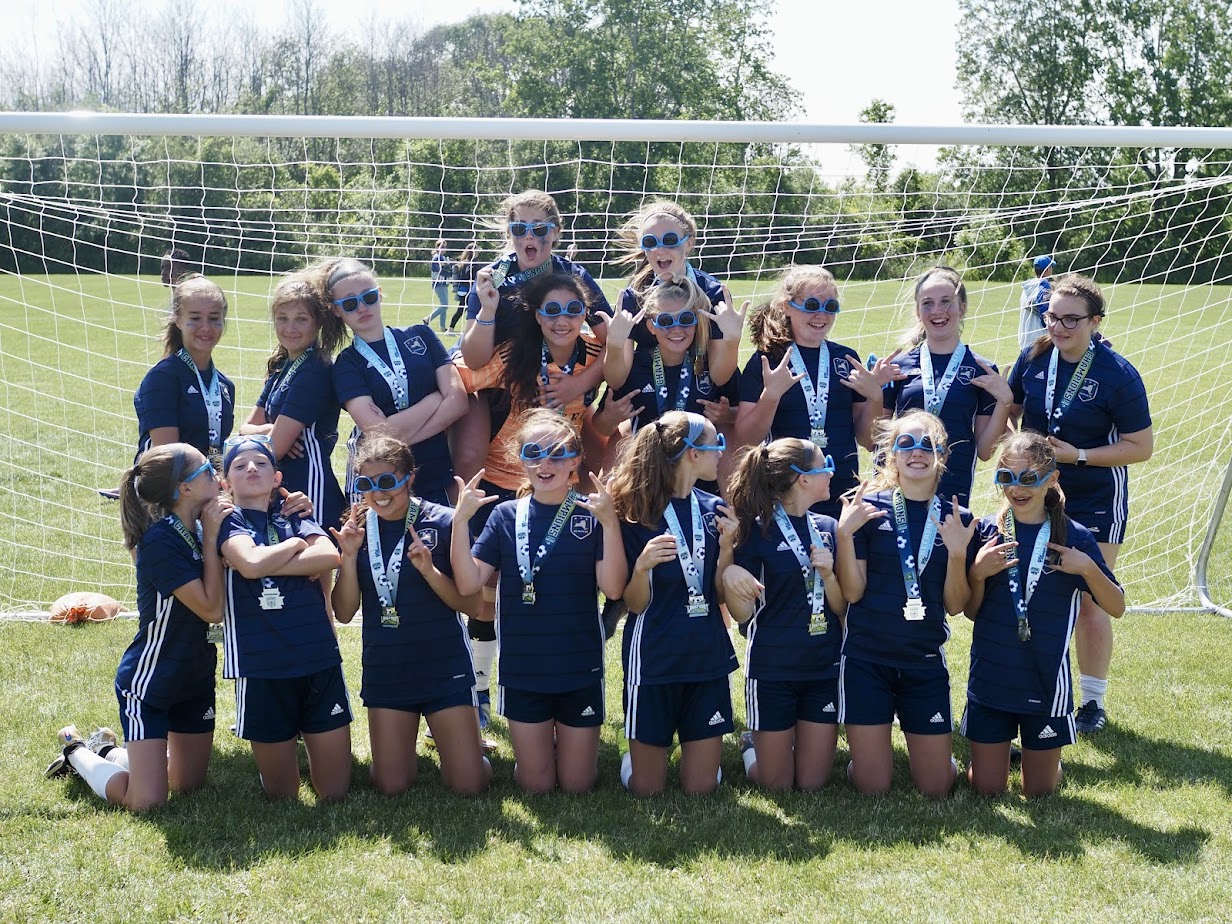 Tournament winning girls soccer team posing having fun and posing with upside-down sunglasses.